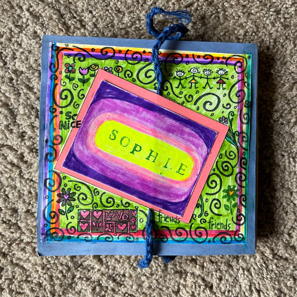 the title page of an accordian book, decorated in green swirly abstractions with a pink and purple name plate reading "Sophie"
