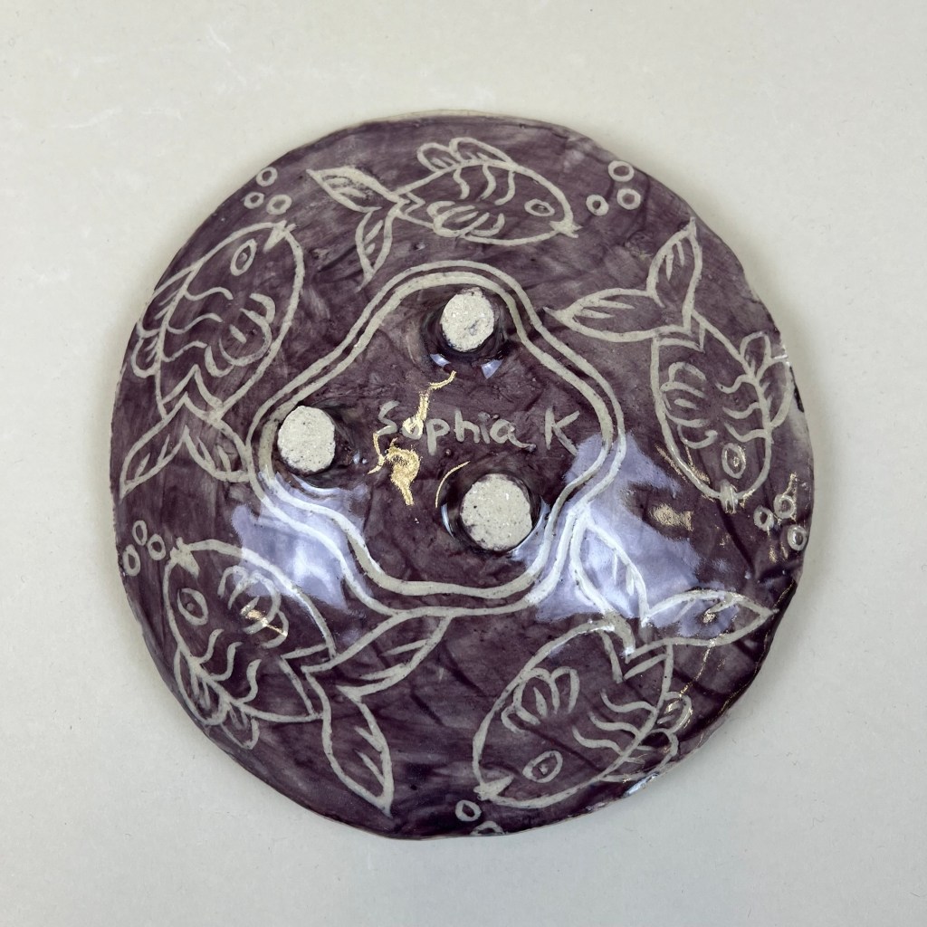 bottom of a purple plate with five fish drawings