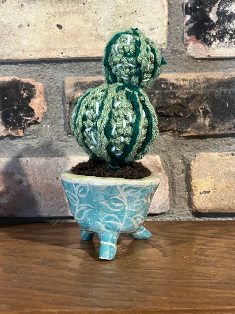 planter, pattened with leaf doodles, with a crocheted cactus inside