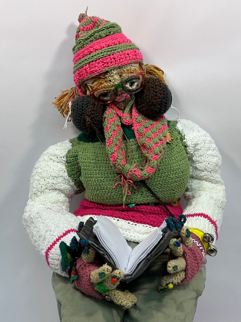 crocheted self portrait of Sophia reading a book